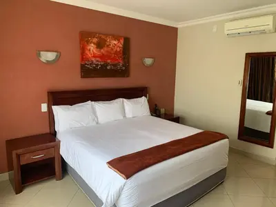 a bedroom with a large white bed and a window at Royal Hotel in Polokwane