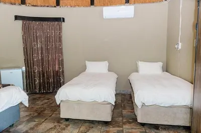 two beds in a room with white sheets and pillows at Mabalel Lodge in Nelspruit