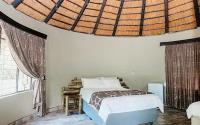 a bedroom with a bed and a large window at Mabalel Lodge in Nelspruit