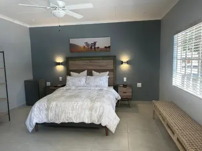 a bedroom with a large bed and a ceiling fan at Mabalel Lodge in Nelspruit