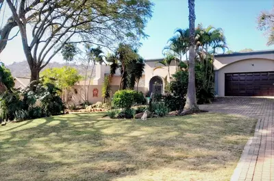 a house with palm trees and a driveway at Barberton BnB in Barberton
