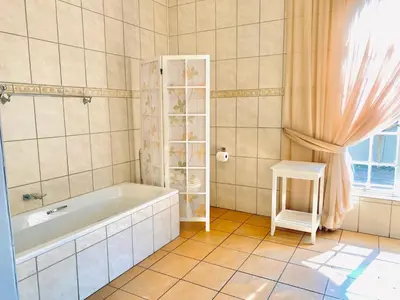 a bathroom with a bath tub and a window at Barberton BnB in Barberton