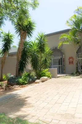 a house with palm trees in front of a driveway at Barberton BnB in Barberton