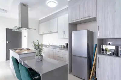 a kitchen with a table with chairs and a refrigerator at Alimama Spaces: The Manson's 8 On New in Midrand