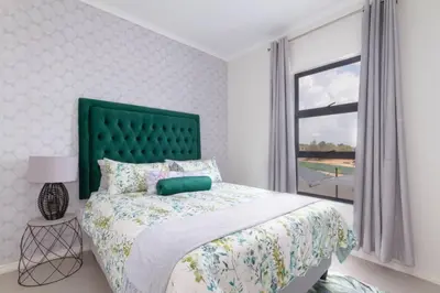 a bedroom with a bed with a green headboard and a window at Alimama Spaces: The Manson's 8 On New in Midrand