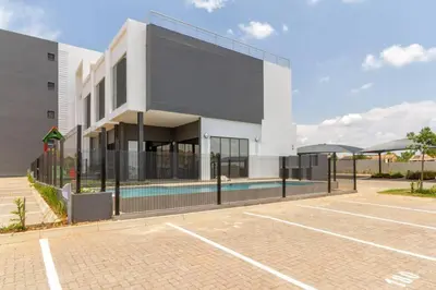 a building with a swimming pool next to a tennis court at Alimama Spaces: The Manson's 8 On New in Midrand