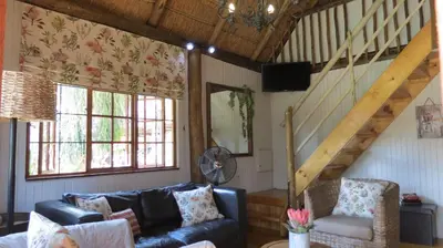 a living room with a couch and a staircase at Ciara Guesthouse in Pretoria