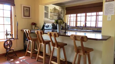 a kitchen with a counter with four wooden bar stools at Ciara Guesthouse in Pretoria