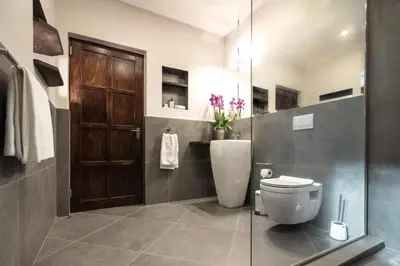 a bathroom with a toilet and a sliding glass door at Kruger Eden Lodge in Marloth Park