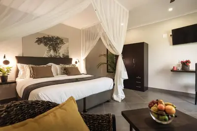 a bedroom with a bed and a table with a bowl of fruit at Kruger Eden Lodge in Marloth Park
