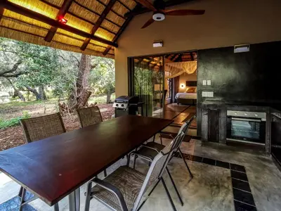 a dining room with a table and chairs and a fireplace at Kruger Eden Lodge in Marloth Park