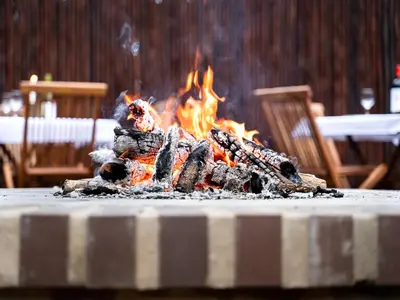 a fire is burning in a table with chairs at Kruger Eden Lodge in Marloth Park