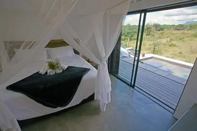 a bedroom with a bed and a view of a pool at Kruger Cliffs Lodge - Absolute privacy guaranteed in Hoedspruit