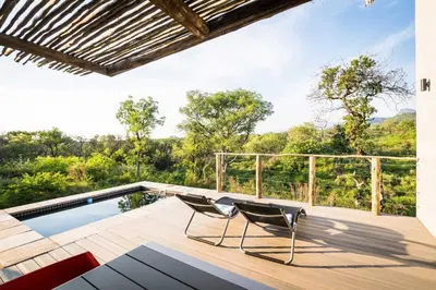 a deck with two chairs and a swimming pool at Kruger Cliffs Lodge - Absolute privacy guaranteed in Hoedspruit