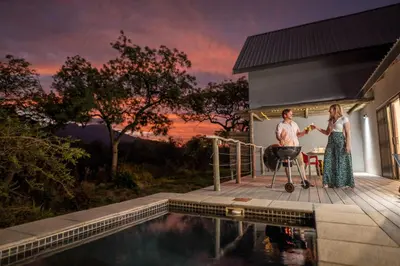 a man and woman standing on a deck next to a swimming pool at Kruger Cliffs Lodge - Absolute privacy guaranteed in Hoedspruit