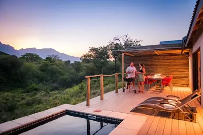 a man and woman standing on a deck next to a pool at Kruger Cliffs Lodge - Absolute privacy guaranteed in Hoedspruit