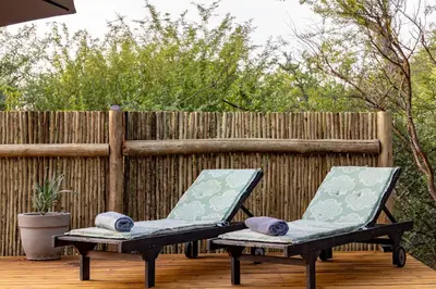 two chairs sitting on a deck in front of a fence at 444 on Taaibos Bush Villa in Hoedspruit