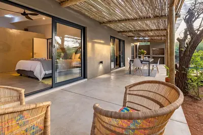 a patio with a bed and a table and chairs at 444 on Taaibos Bush Villa in Hoedspruit