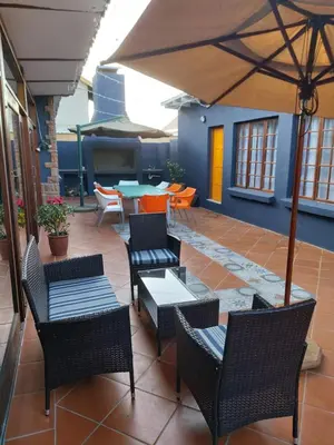 a patio with chairs and tables and an umbrella at Green Venus in Kaapsehoop