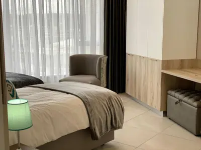 a bedroom with a bed and a chair and a window at Menlyn Maine Residence 11th Floor Apartment in Pretoria
