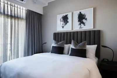 a bedroom with a large bed with white sheets and pillows at The Capital Trilogy Menlyn Maine in Pretoria