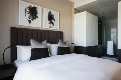 a bedroom with a large bed with black and white pillows at The Capital Trilogy Menlyn Maine in Pretoria