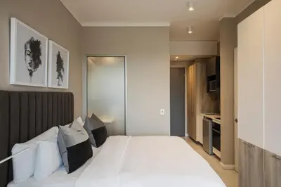 a bedroom with a large bed with white sheets and pillows at The Capital Trilogy Menlyn Maine in Pretoria