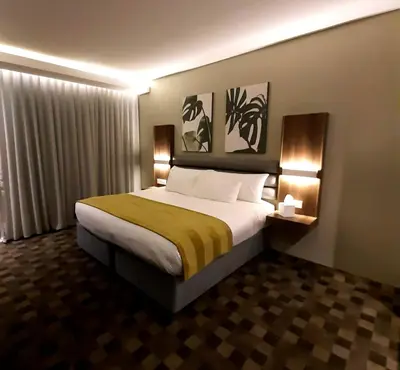 a hotel room with a large bed with two lamps at Copperwood Hotel and Conferencing in Brits