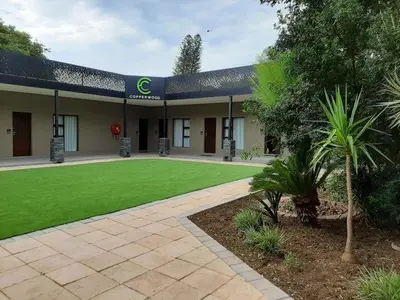 a building with a green lawn in front of it at Copperwood Hotel and Conferencing in Brits