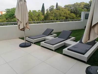 a balcony with two chairs and an umbrella at Regency Apartment Hotel Menlyn in Pretoria