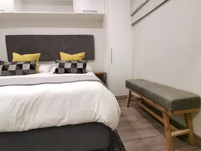 a bedroom with a large bed and a bench at Regency Apartment Hotel Menlyn in Pretoria