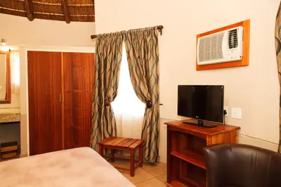 a bedroom with a bed and a television on a table at Tshipise A Forever Resort in Tshipise