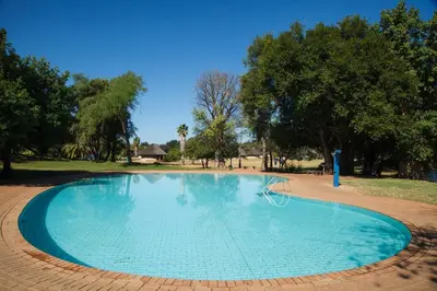 a large swimming pool in a park with trees at Tshipise A Forever Resort in Tshipise