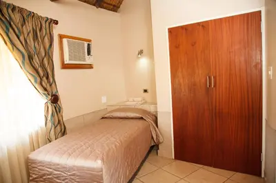 a small bedroom with a bed and a wooden door at Tshipise A Forever Resort in Tshipise
