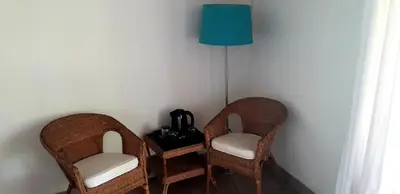 two wicker chairs and a lamp in a room at Lovely holiday home for a large family or friends bordering Kruger National Park in Marloth Park