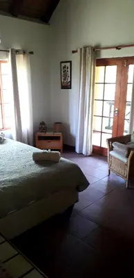 a bedroom with a bed and a chair and windows at Lovely holiday home for a large family or friends bordering Kruger National Park in Marloth Park