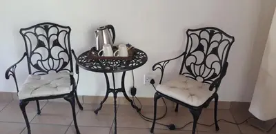 two chairs and a table with a tea kettle on it at Lovely holiday home for a large family or friends bordering Kruger National Park in Marloth Park