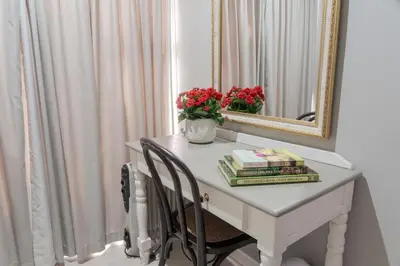 a white desk with a mirror and a vase of flowers at Rueby’s Guesthouse in Dullstroom
