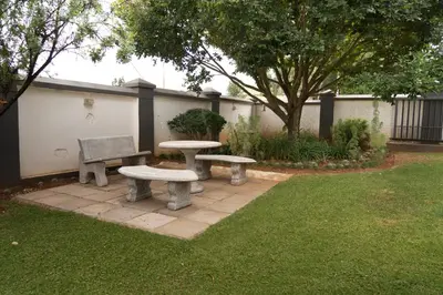 two picnic tables and a bench in a yard at Rueby’s Guesthouse in Dullstroom