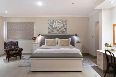 a bedroom with a large bed and a chair at Rueby’s Guesthouse in Dullstroom