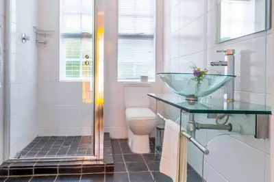 a bathroom with a glass sink and a toilet at Middelberg Manor in Pretoria