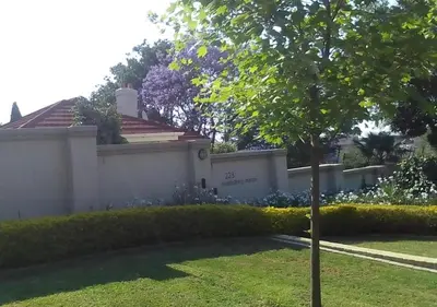 a tree in a yard next to a white fence at Middelberg Manor in Pretoria