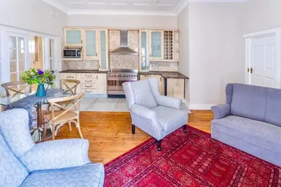 a living room with two chairs and a table and a kitchen at Middelberg Manor in Pretoria