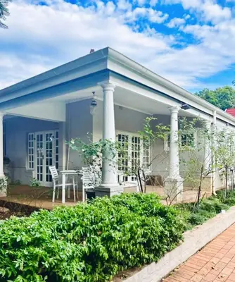 a white house with a blue roof and a table at Middelberg Manor in Pretoria