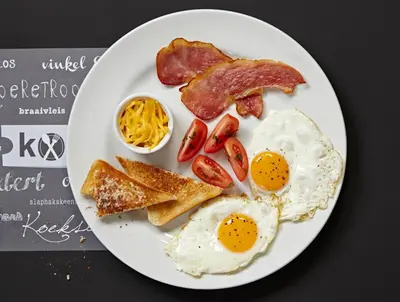 a plate of breakfast food with eggs bacon and toast at ATKV Klein-Kariba in Bela-Bela