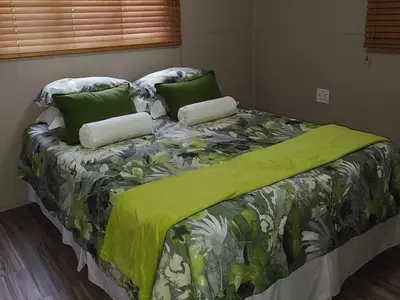 a bed with a green blanket and pillows on it at Sarah's Place Guesthouse in Pretoria