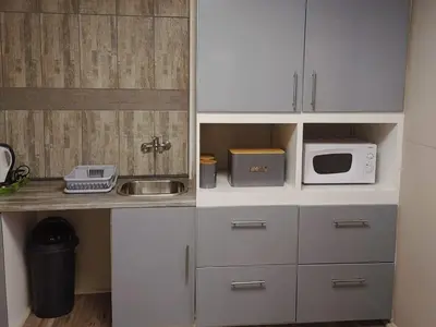 a kitchen with white cabinets and a microwave at Sarah's Place Guesthouse in Pretoria