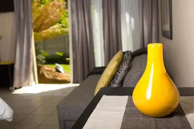 a yellow vase sitting on a table next to a couch at Sarah's Place Guesthouse in Pretoria