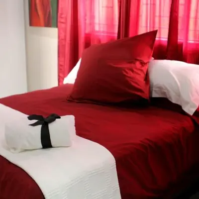 a red and white bed with a black bow tie on it at Sarah's Place Guesthouse in Pretoria