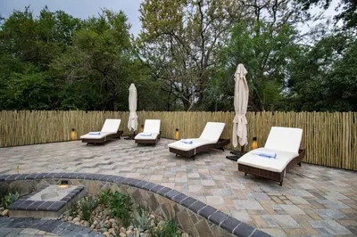 a patio with chairs and umbrellas and a fence at Little Africa Safari Lodge in Hoedspruit